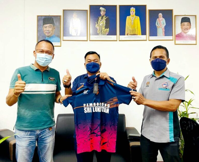 Sani Haji Miasin (tengah) yang juga Pengurus Pasukan Bolasepak SAFA Zon Pantai Barat Selatan menerima sumbangan jersi daripada Pengarah Urusan Pemborong Sri Lukutan, Sipitang, Yeo Chien Lun (kiri).